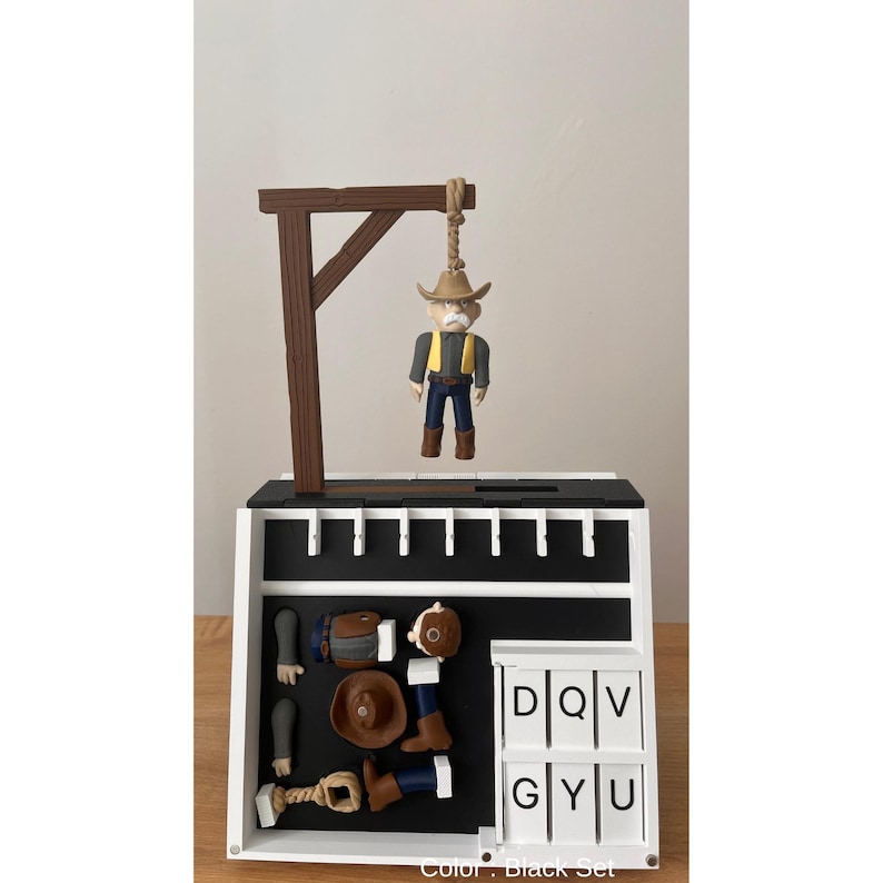 May include: A black and white cowboy-themed game set. The set includes a miniature gallows with a cowboy figure, along with various game pieces and letter tiles. The color of the set is black.