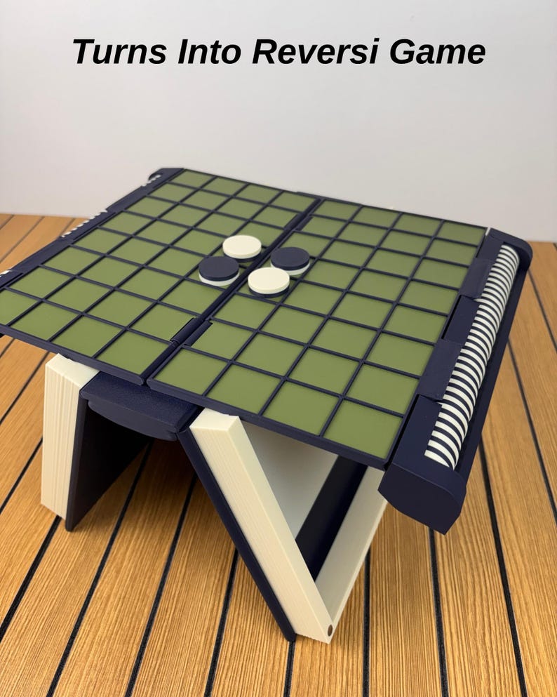 以下が含まれることがあります： Turns Into Reversi Gameというテキストが書かれた折りたたみ式のボードゲーム。ダークブルーのフレーム、オリーブグリーンのグリッド面、白とダークブルーの円形の駒が特徴です。構造はオフホワイトの斜めの脚で支えられています。
