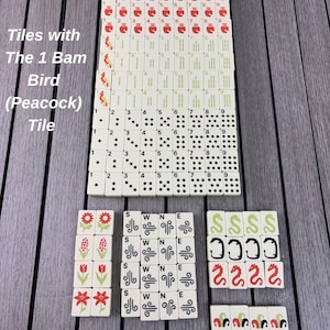 May include: A complete set of off-white Mahjong tiles arranged in rows. The tiles feature red character symbols, green bamboo sticks, black dots, flower illustrations, directional letters S, W, N, E, dragons, and the 1 Bam Bird Peacock tile.