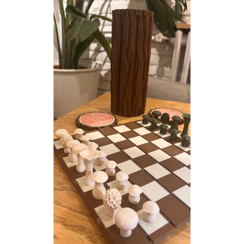 K&ouml;nnte beinhalten: Ein skurriles Schachspiel mit pilzf&ouml;rmigen Figuren auf einem braun-wei&szlig;en Schachbrett. Eine hohe, braune, baumstammf&ouml;rmige Vase und zwei Untersetzer aus Holz sind ebenfalls vorhanden. Die Schachfiguren sind in verschiedenen Wei&szlig;- und Beiget&ouml;nen gehalten.