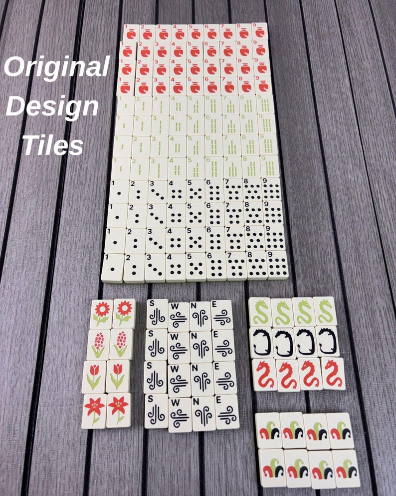 May include: A collection of off-white Mahjong tiles arranged in rows. The set includes numbered tiles in red and green, dot tiles, flower tiles, wind tiles marked S, W, N, E, and dragon tiles in green, black, and red. The text Original Design Tiles is visible.