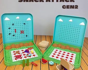 May include: Two Snack Attack Gen2 board games featuring teal cases with grid-based play areas, red and white checkered picnic blankets, miniature food pieces, small brown baskets, and green grass-like textures with ant markers.