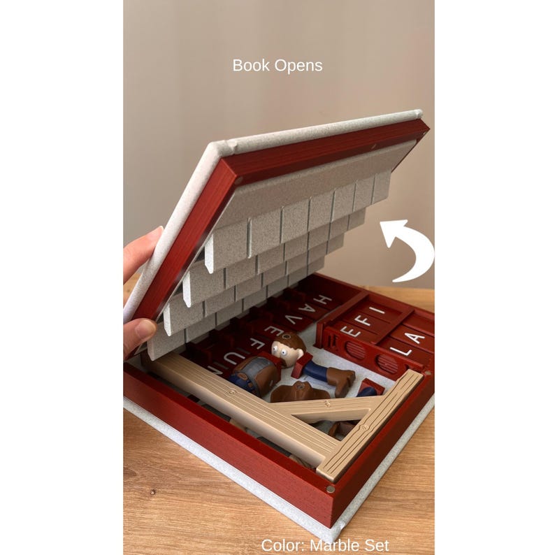 May include: A red and white marble set box with a hinged lid. The lid is open, revealing a gray roof-like structure and the words "HAVE FUN" and "EFI LA" on the inside. The box contains small toys.