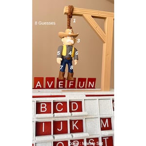 May include: A word game set with a cowboy figure suspended from a wooden gallows. The game includes red letter tiles spelling "AVE FUN" and a board with letter slots. The text "8 Guesses" is visible.
