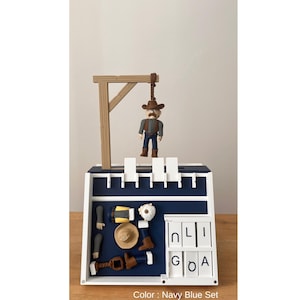 May include: A navy blue set featuring a miniature cowboy figure hanging from a wooden gallows. The set includes cowboy accessories and the text "N L I G O A".
