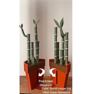 May include: A burnt orange pot-shaped Post-it Note dispenser with olive green bamboo stalks and leaves. The bamboo stalks have white bands. The text "Post it Note Dispancer" and "Color: BurntOrange Pot Olive Green Bamboos" is visible.