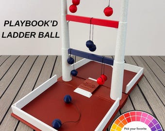 May include: A Playbook'd Ladder Ball game set featuring a red base with white borders, two white vertical posts, and three horizontal bars labelled 1, 2, and 3. Red and blue balls attached to strings hang from the bars, with additional balls on the base.
