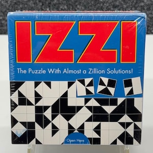 May include: A boxed puzzle game with the word "IZZI" in large red letters on a blue background. The box also features the text "The Puzzle With Almost a Zillion Solutions!" and a black and white geometric pattern.