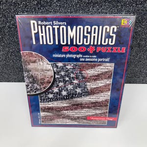 Peut inclure: Un puzzle Photomosaics de 500 pièces de Robert Silvers. Le puzzle représente un drapeau américain composé de photographies miniatures. La boîte est bleue avec des accents rouges et blancs et le texte "American Flag". Le puzzle mesure 45.7 x 45.7 cm.