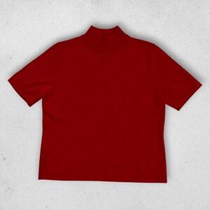 May include: A solid deep red short-sleeve shirt featuring a mock neck collar. The garment is constructed with a simple, clean design, showcasing a consistent dark crimson hue throughout the fabric, including the sleeves and the high neckline.