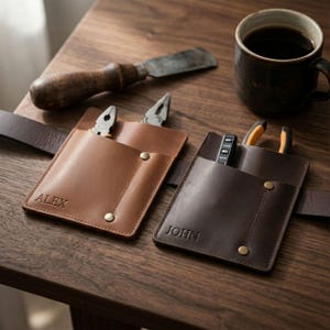 May include: Two leather tool pouches attached to a belt, one tan with the name ALEX and one dark brown with the name JOHN. Each pouch features metal rivets and holds small pliers. The pouches are made of smooth leather with visible stitching.