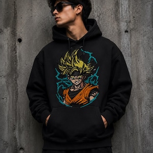May include: A black hooded sweatshirt featuring a large, detailed graphic print of an anime character with spiky yellow hair, wearing an orange gi, surrounded by blue lightning effects. The hoodie includes a front kangaroo pocket and long sleeves.