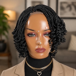May include: A black braided wig styled in a short, curly bob. The wig is on a mannequin head with makeup, a nose ring, and gold jewelry, including a necklace with a heart pendant. The mannequin is wearing a black turtleneck and a tan blazer.