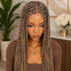 May include: A mannequin head featuring long, straight, micro-braided hair in a blend of dark brown and honey blonde tones. The hair is parted down the centre, with a natural-looking scalp appearance at the part, and falls straight down the shoulders.