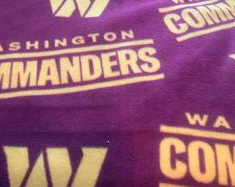 May include: Purple fleece blanket with a repeated pattern of the Washington Commanders logo and the team's "W" logo. The logo is in a yellow color.