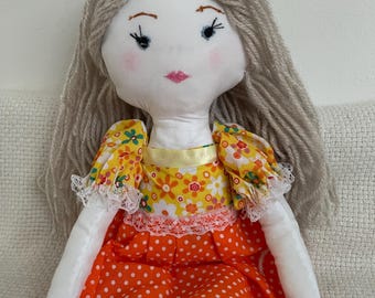 Muñeca de trapo hecha a mano de color naranja y amarillo.