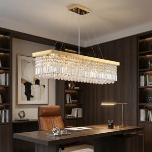 May include: A rectangular chandelier featuring a gold-toned metal frame and multiple tiers of clear, faceted crystal prisms hanging in a dense, uniform arrangement, suspended from the ceiling by thin wires attached to a matching gold canopy.