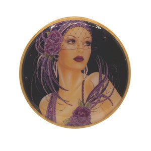 May include: Circular decorative item with a vintage illustration of a woman in a flapper-style outfit. The woman has dark red lipstick, and is wearing a purple headpiece with a veil and a purple rose. The background is black, and the border is gold.