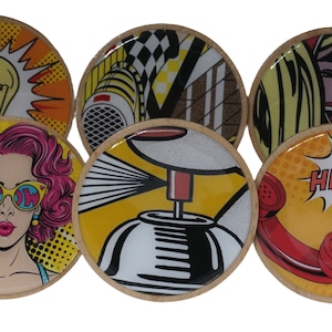 May include: Six round coasters with a pop art design. The coasters feature a lightbulb, a spray can, a telephone, a woman with sunglasses, a woman with blonde hair, and a checkered pattern.