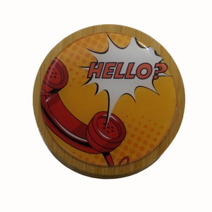 May include: A round wooden coaster featuring a red telephone graphic and the text "HELLO?" in a comic book style speech bubble. The background is yellow with white polka dots.