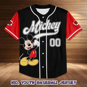 May include: Black baseball jersey with red sleeves and white accents. Features the word "Mickey" in white script, a cartoon image of Mickey Mouse, and the number "00". The text "KID, YOUTH BASEBALL JERSEY" is at the bottom.