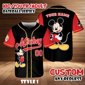 May include: Black baseball jersey with red sleeves and yellow trim. Features the name "Mickey" in red script, the number "00", and a Mickey Mouse graphic. The back of the jersey has a large Mickey Mouse graphic and the text "YOUR NAME". The jersey is labeled "STYLE 1".