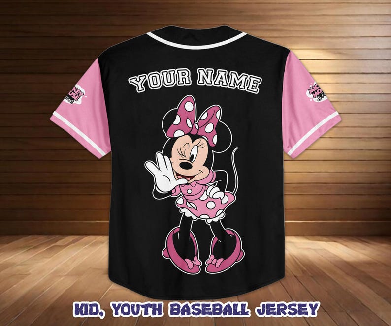 May include: Black baseball jersey with pink sleeves and white trim. Features a Minnie Mouse graphic on the back, with the text "YOUR NAME" above the graphic. The text "KID, YOUTH BASEBALL JERSEY" is at the bottom.