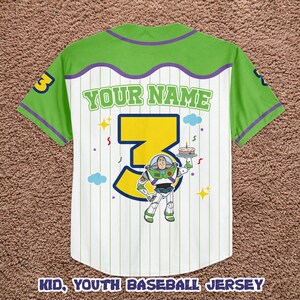 May include: White youth baseball jersey with green and purple accents. Features a large yellow number 3, Buzz Lightyear graphic, and the text "YOUR NAME". The jersey has vertical stripes and the text "KID, YOUTH BASEBALL JERSEY" at the bottom.