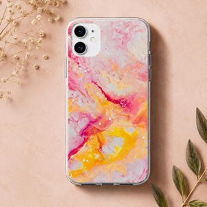 Pode incluir: Uma capa de telemóvel transparente com um design de arte fluida abstrata, apresentando redemoinhos vibrantes de rosa choque, amarelo brilhante e tons suaves de pêssego. A capa tem um recorte para câmara dupla no canto superior esquerdo.