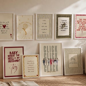 May include: A collection of framed art prints with various quotes and illustrations. The prints feature a mix of typography and graphic designs in neutral tones, with pops of red and gold. The art is displayed on a white wall, creating a gallery-like aesthetic.