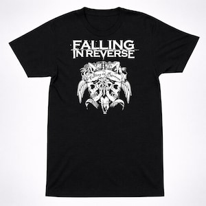 以下が含まれることがあります： 白文字で「FALLING IN REVERSE」と書かれた黒いTシャツ。2つのドクロ、翼、バナーのグラフィックの上にあります。バナーには「Falling in Reverse」と書かれています。