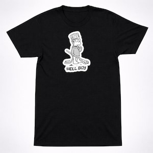 May include: Black t-shirt featuring a cartoon illustration of a character holding a trident. The character is wearing glasses and a sweater. The text "HELL BOY" is below the character in a white font.