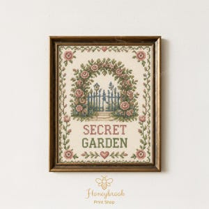 May include: A framed cross-stitch embroidery featuring a floral archway over a blue gate, with the text "SECRET GARDEN" in pink and green lettering. The design is bordered by pink roses and green vines on a cream-colored fabric background.
