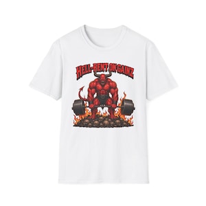 May include: White t-shirt featuring a muscular red devil lifting a barbell over a pile of skulls. The graphic includes the text "HELL-BENT ON GAINZ" in red, stylized lettering. The design incorporates flames for a bold, eye-catching look.