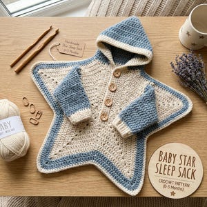 Può includere: Un sacco nanna all'uncinetto a forma di stella con cappuccio, in filato color crema e blu, con quattro bottoni in legno e un'etichetta con scritto Handmade Star Sleep Sack 0-3 Months. Un disco in legno riporta BABY STAR SLEEP SACK CROCHET PATTERN 0-3 Months.