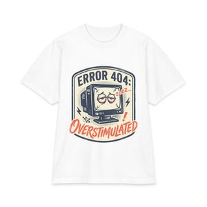 May include: A white short-sleeve t-shirt featuring a graphic of a tired computer monitor with red eyes and the text ERROR 404: OVERSTIMULATED. The design includes a cream-colored background, dark blue outlines, and red accents on the screen.
