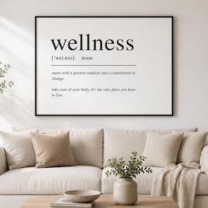 May include: A rectangular wall art print in a black frame featuring the word wellness in a dictionary definition style. The text includes the phonetic spelling, the noun label, and two sentences about positive mindset and body care.