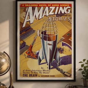 Könnte beinhalten: Ein gerahmtes, vintage Science-Fiction-Magazin-Cover mit dem Titel Amazing Stories, das eine große silberne Rakete im Bau, einen orangefarbenen Kran und einen Zug zeigt, mit dem Text A Smashing Novel of Super Science und The Brain von Alexander Blade.
