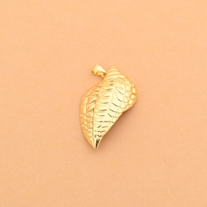 Può includere: Un ciondolo in metallo color oro a forma di conchiglia, caratterizzato da una superficie testurizzata con creste orizzontali e un piccolo occhiello sulla parte superiore per l'aggancio. Il ciondolo ha una finitura lucida e una forma curva.