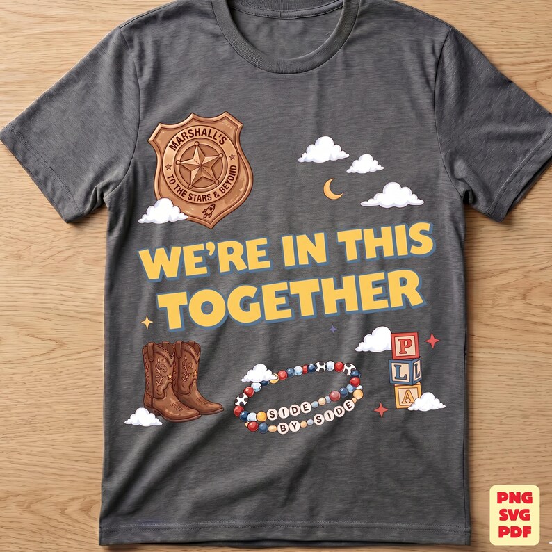 Op de afbeelding: Een donkergrijs t-shirt met een grafische print van een bruine sheriffster met de tekst Marshall To The Stars & Beyond, de tekst WE'RE IN THIS TOGETHER, bruine cowboylaarzen, een kleurrijke kralenarmband met de tekst SIDE BY SIDE en blokken.