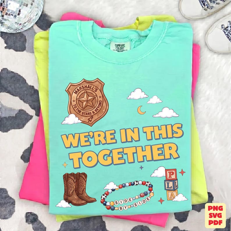 Op de afbeelding: Een mintgroen t-shirt met een afbeelding van een bruine sheriffster met de tekst Marshall's To The Stars & Beyond, wolken, een maansikkel, bruine cowboylaarzen, een kleurrijke kralenarmband en blokken met de letters P, L, A.