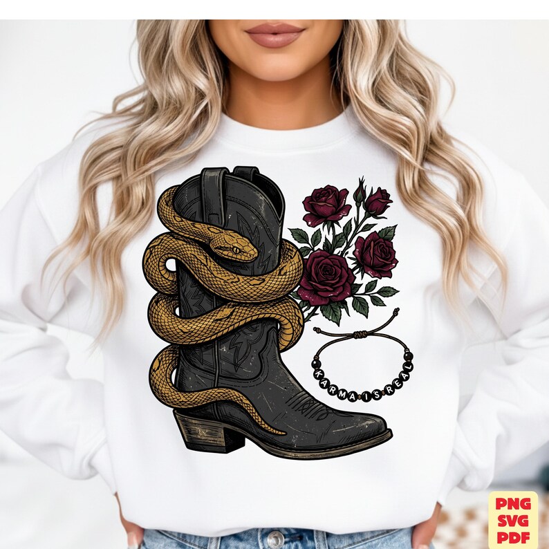 May include: A white sweatshirt featuring a graphic print of a black cowboy boot wrapped in a golden snake, accompanied by dark red roses and a beaded bracelet with the text "KARMA IS REAL" printed in black letters on the beads.