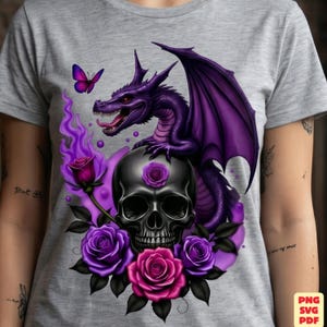May include: A heather gray t-shirt featuring a graphic print of a purple dragon perched atop a black skull. The design includes vibrant purple and pink roses, a small purple butterfly, and swirling purple flames surrounding the central skull.