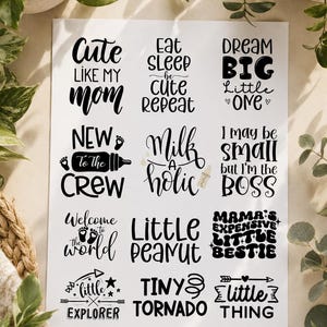May include: A white sheet featuring twelve black graphic designs with baby-themed phrases including Cute Like My Mom, Eat Sleep Be Cute Repeat, Dream Big Little One, New To The Crew, Milk-A-Holic, I May Be Small But I'm The Boss, Welcome To The World, Little Peanut, Mama's Expensive Little Bestie, Little Explorer, Tiny Tornado, and Little Thing.