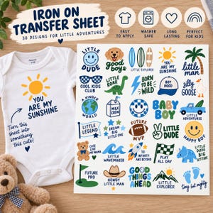 May include: A white baby bodysuit featuring a yellow sun graphic and the text You Are My Sunshine, alongside an iron-on transfer sheet with 30 colorful designs including a dog, dinosaur, rocket, and various phrases like Little Dude and Little Legend.