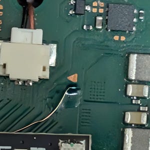 K&ouml;nnte beinhalten: Nahaufnahme einer gr&uuml;nen Leiterplatte mit verschiedenen elektronischen Bauteilen. Ein wei&szlig;er Stecker, Kupferdraht und mehrere kleine, rechteckige und quadratische Bauteile sind sichtbar. Die Platine hat Kupferspuren und L&ouml;tstellen.