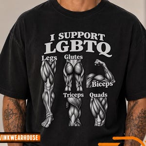 Könnte beinhalten: Ein schwarzes Kurzarm-T-Shirt mit dem weißen Text I SUPPORT LGBTQ über anatomischen Illustrationen von Muskeln, die als Legs, Glutes, Biceps, Triceps und Quads beschriftet sind. Das Design ist mittig auf der Brust platziert.