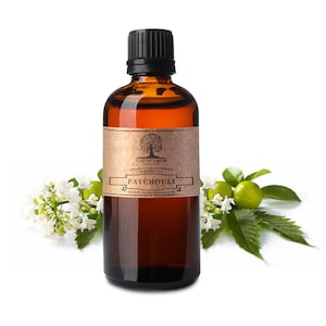 May include: A brown glass bottle of patchouli essential oil with a black cap and a tan label. The label reads "Patchouli" and "Nature's Note Organics." White flowers and green leaves surround the bottle, set against a white background.