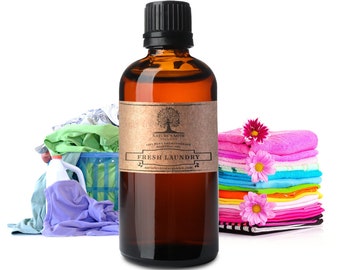 Może przedstawiać: Brązowa szklana butelka z czarną zakrętką i brązową papierową etykietą. Etykieta zawiera napis "Nature's Note 100% Pure Aromatherapy Essential Oil Fresh Laundry naturesnotesorganics.com". Butelka stoi na białym tle, na tle kolorowej sterty prania.