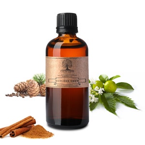 May include: A brown glass bottle with a black cap, labeled "Nature's Note 100% Pure Aromatherapy Essential Oil Witches Brew naturesnoteorganics.com". The bottle is surrounded by pine cones, cinnamon sticks, and green leaves.